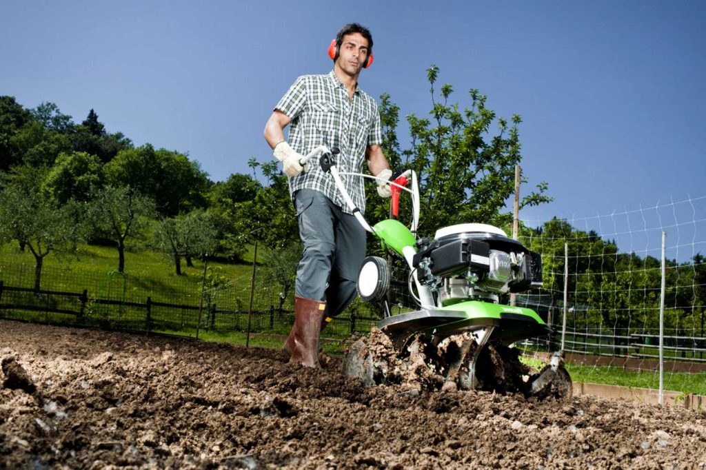 Herse la terre avec un tracteur à conducteur marchant